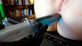 Dominatriz aplicando un enema con una jeringa enorme